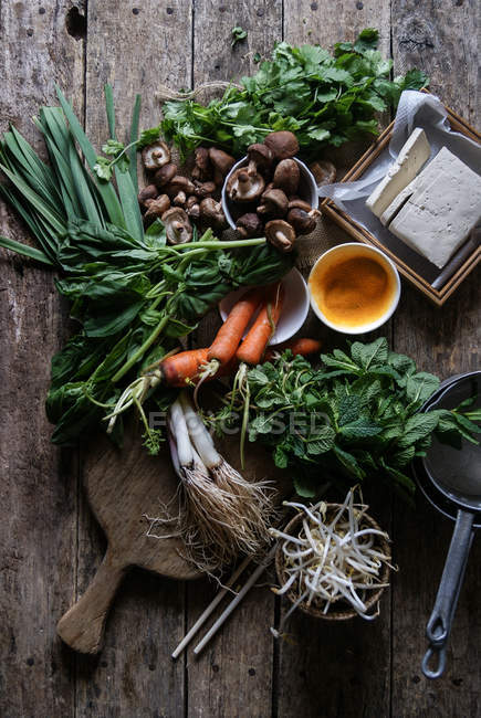 Verduras arregladas en mesa rústica para preparar crepe tradicional Banh Xeo - foto de stock