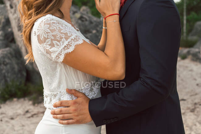 Vista lateral da colheita de homem terno alegre e mulher tocando com narizes e olhando um para o outro com amor no dia do casamento — Fotografia de Stock