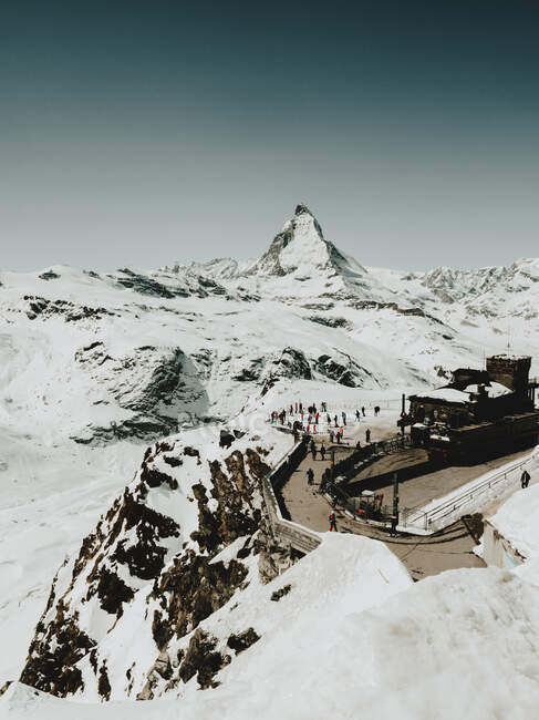 Grupo de turistas irreconocibles en mirador en montañas nevadas. - foto de stock