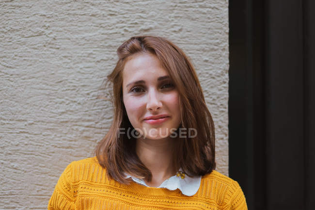 Lächelnde Frau in gelber Strickjacke blickt auf der Straße in die Kamera — Stockfoto