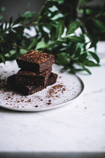 Scheiben veganen Brownie auf Teller auf weißer Tischplatte — Stockfoto