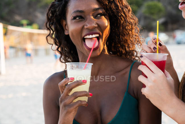 Donne giocose che si godono un drink sulla spiaggia — Foto stock