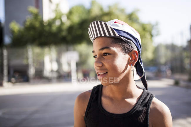 Jovem afro menino com boné e bandana de pé ao ar livre — Fotografia de Stock