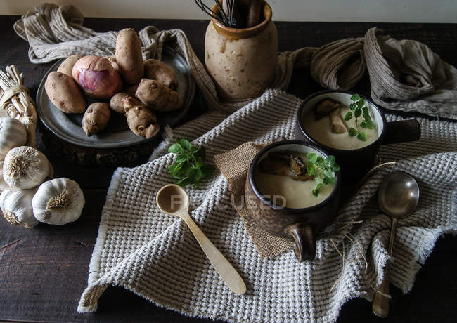 Bowls of tasty Jerusalem artichoke soup with ingredients on rustic wooden table — Stock Photo