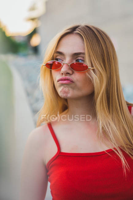 Junge Frau im Tank-Top und Sonnenbrille grimmig im Freien — Stockfoto
