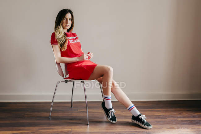 Pretty woman in red outfit sitting on chair — Stock Photo