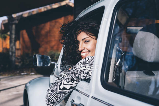 Молодая женщина сидит внутри ретро автомобиля в сельской местности и смотрит в камеру — стоковое фото