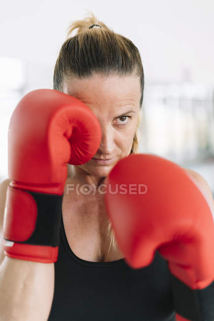 Взрослая женщина в боксёрских перчатках стоит в боевой позиции — стоковое фото