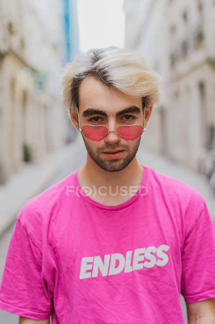 Portrait of stylish man in pink heart-shaped sunglasses standing on street — Stock Photo