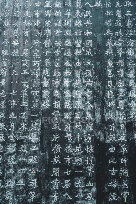 Фон обветшалой каменной стены с резными иероглифами — стоковое фото