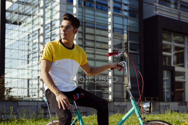 Jovem atraente sentado na bicicleta vintage — Fotografia de Stock