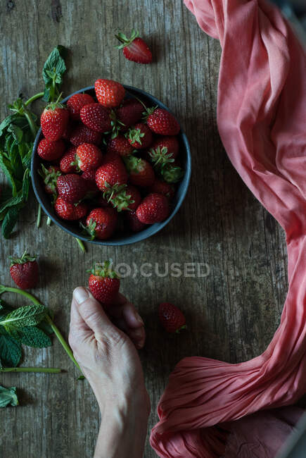 Hand nimmt leckere Erdbeeren aus Schüssel — Stockfoto