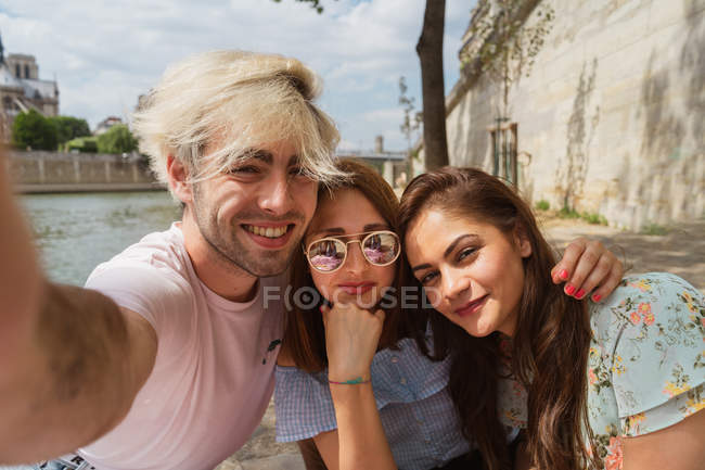 Souriant les jeunes femmes et l'homme en vêtements décontractés prendre selfie à l'extérieur — Photo de stock