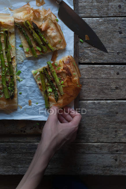 Mão humana tomando pedaço de torta de espargos — Fotografia de Stock