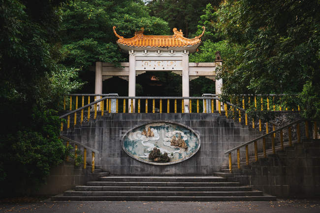 Extérieur de la façade ornementale en pierre du temple oriental au milieu d'une végétation luxuriante dans la montagne Qingxiu, Nanning, Chine — Photo de stock