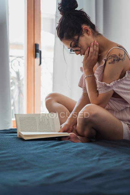 Sensual morena mulher com livro refrigeração na cama — Fotografia de Stock