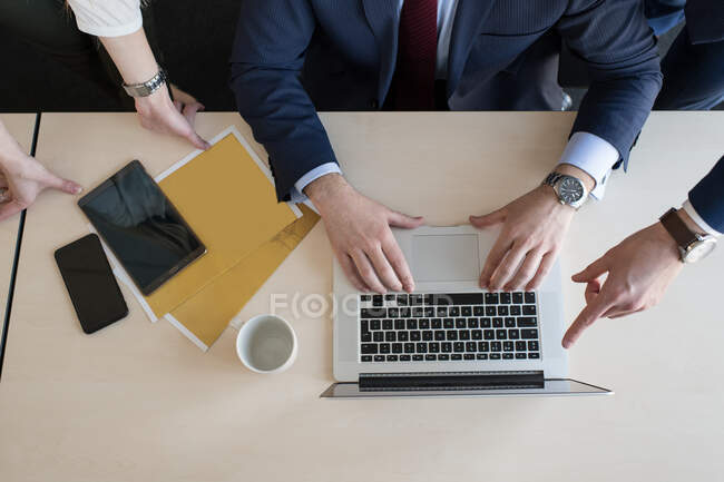 Стильные коллеги собираются вокруг ноутбука в офисе — стоковое фото