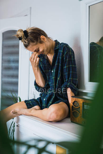 Lachende Frau in kariertem Oversize-Hemd sitzt neben Funkgerät — Stockfoto