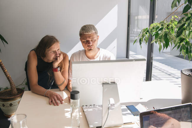 Men sitting at tables in front of each other inside of open space office and working on computers in sunlight — Stock Photo