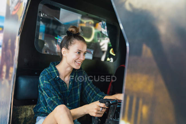 Femme en chemise à carreaux jouant machine d'arcade — Photo de stock