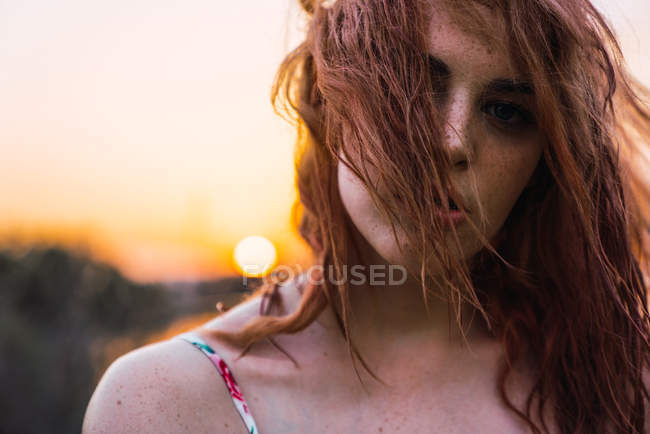 Retrato de una joven pecosa con la cara cubierta de pelo al atardecer - foto de stock