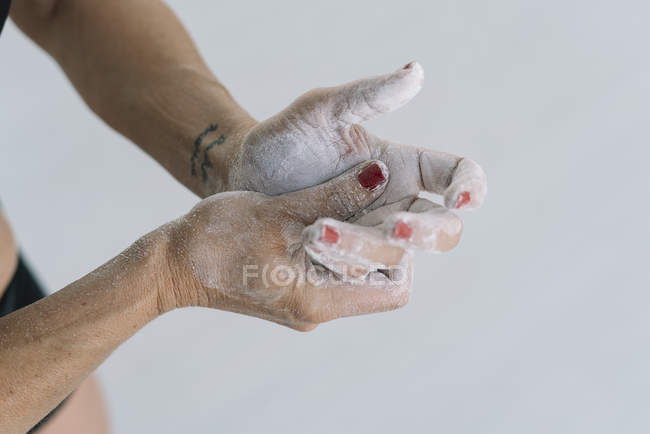 Female hands with tattoo spreading chalk on hands on white background — Stock Photo