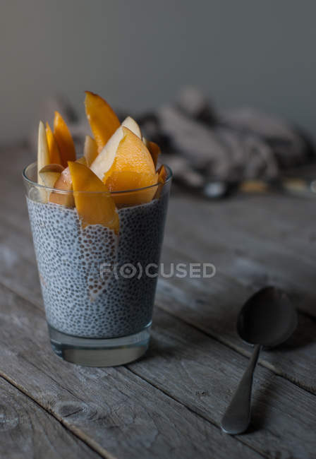 Смачний чіа пудинг з манго в склянці на дерев'яному столі — стокове фото