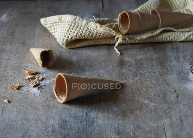 Cônes de gaufres vides pour crème glacée sur table en bois gris — Photo de stock