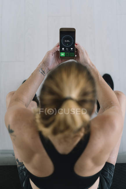 Sportlerin sitzt und nutzt Fitness-App auf Smartphone — Stockfoto