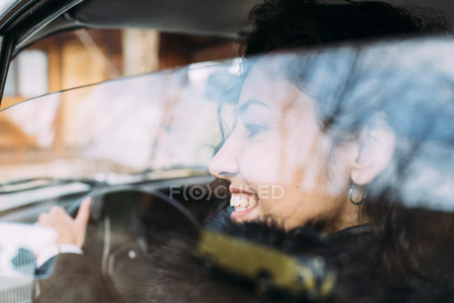 Close-up of smiling young woman driving car — Stock Photo