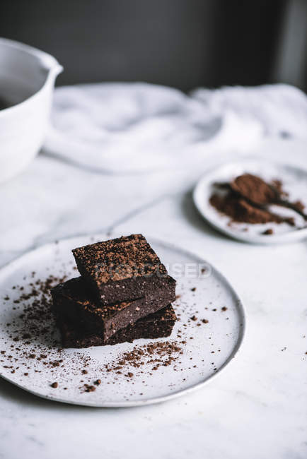 Fatias vegan brownie na placa na mesa branca — Fotografia de Stock
