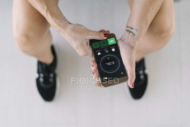 Sportlerin sitzt auf Bank und nutzt Fitness-App auf Smartphone — Stockfoto