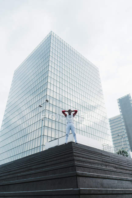 Desportivo afro-americano homem de pé em escadas contra vidro edifício moderno — Fotografia de Stock