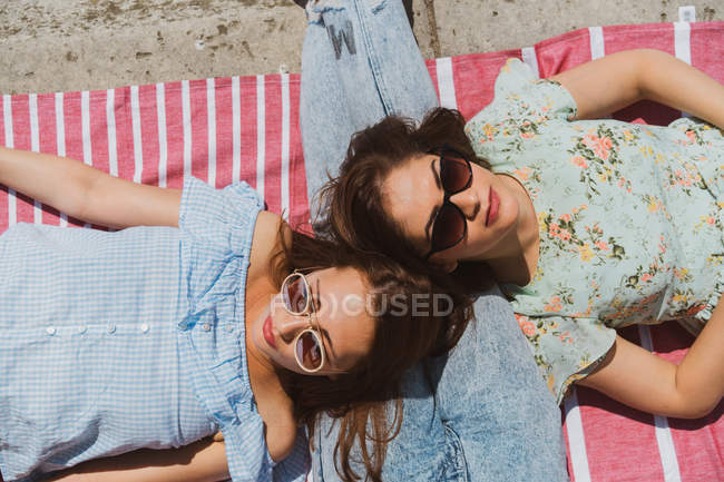 Улыбающиеся подруги в солнечных очках отдыхают на набережной — стоковое фото