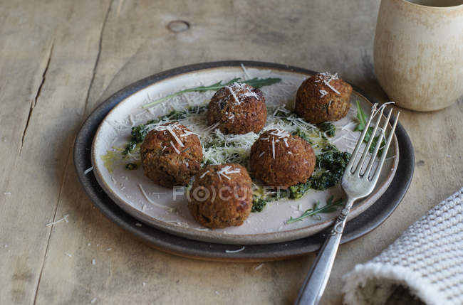 Linsenfleischbällchen garniert mit Rucola-Pesto-Sauce und Käse auf Teller auf Holztisch — Stockfoto