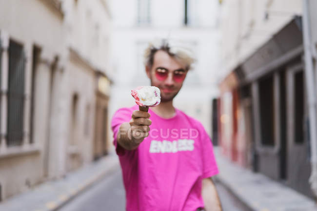 Elegante uomo in t-shirt rosa che mostra il gelato sulla strada — Foto stock