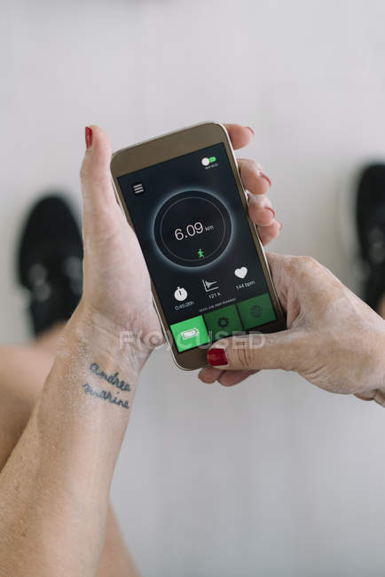 Hände der Sportlerin mit Fitness-App auf dem Smartphone — Stockfoto
