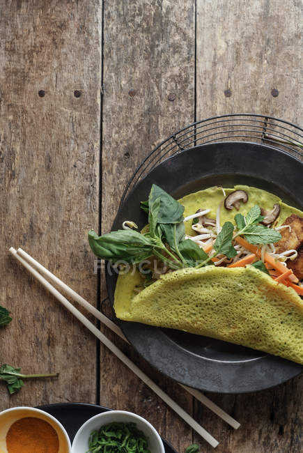 Panqueque frito salado vietnamita con verduras en plato sobre mesa de madera - foto de stock