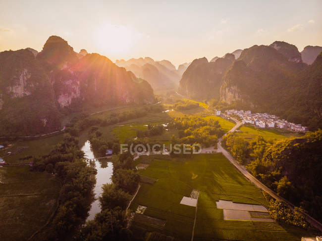 Campos e cidade cercada por montanhas rochosas únicas ao pôr do sol, Guangxi, China — Fotografia de Stock