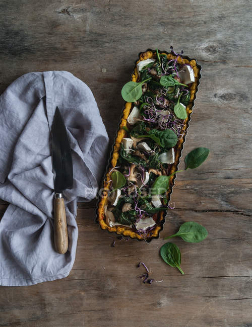 Gebackene Torte mit Polenta und Spinat garniert mit Schrittkäsestücken in Auflaufform auf Holztisch — Stockfoto