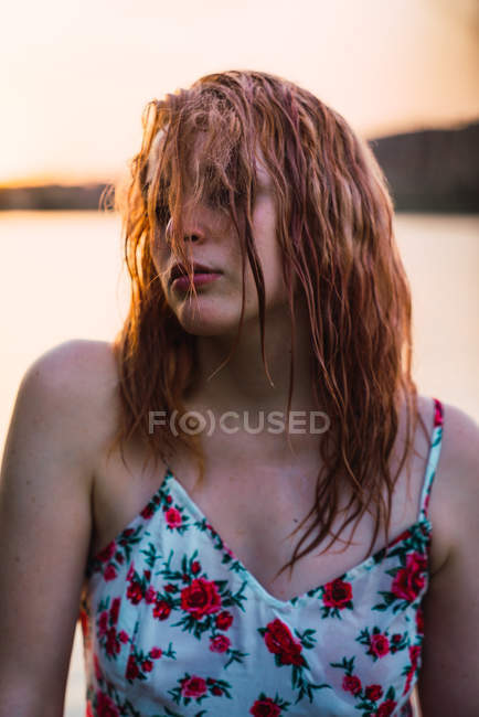 Femme sensuelle en robe avec les cheveux mouillés sur la rive du lac au coucher du soleil — Photo de stock