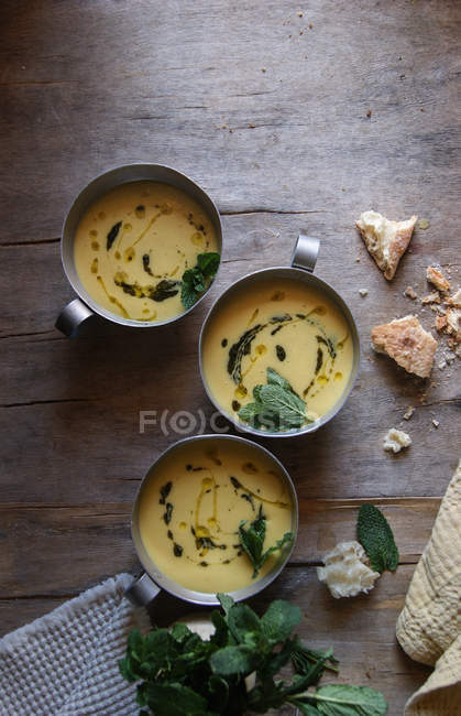 Sopa de crema de maíz con coco y pesto en cuencos sobre mesa de madera - foto de stock