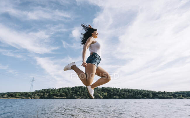 Femme gaie saute au bord du lac. — Photo de stock