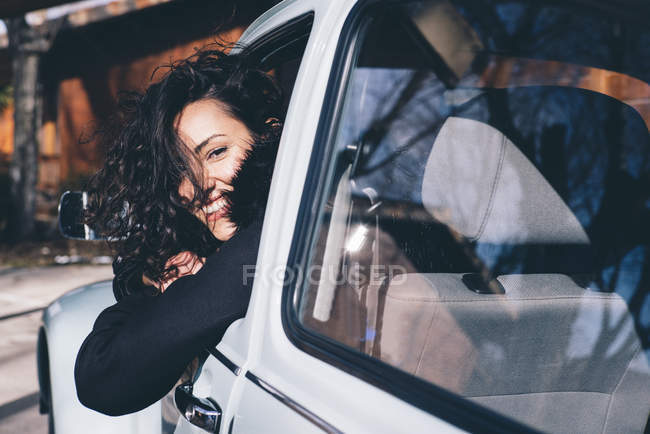 Молода жінка сидить всередині ретро автомобіль в сільській місцевості і дивиться на камеру — стокове фото