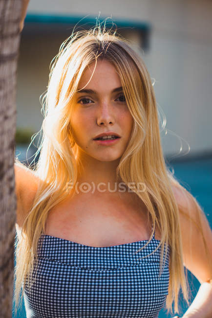 Blonde young woman in stylish outfit standing outdoors in sunlight — Stock Photo