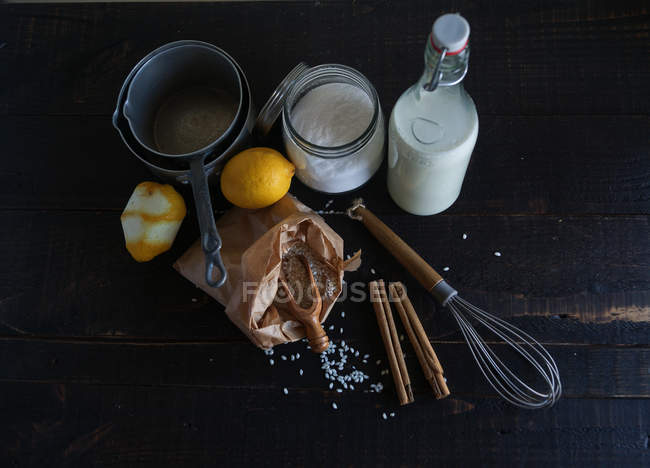 Rustikale Anordnung von Reis, Milch, Gewürzen und Zitronen auf schwarzem Holztisch mit Utensil — Stockfoto