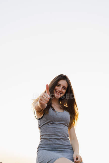Junge brünette Frau steht draußen und zeigt Daumen nach oben Geste — Stockfoto