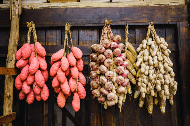 Batatas doces chinesas com amendoim e alho pendurados em cachos na parede de madeira — Fotografia de Stock