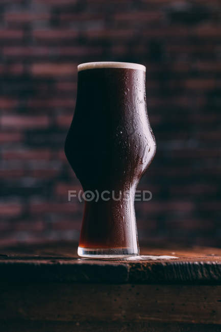 Холодне стокове пиво в склянці на дерев'яному столі на темному фоні — стокове фото