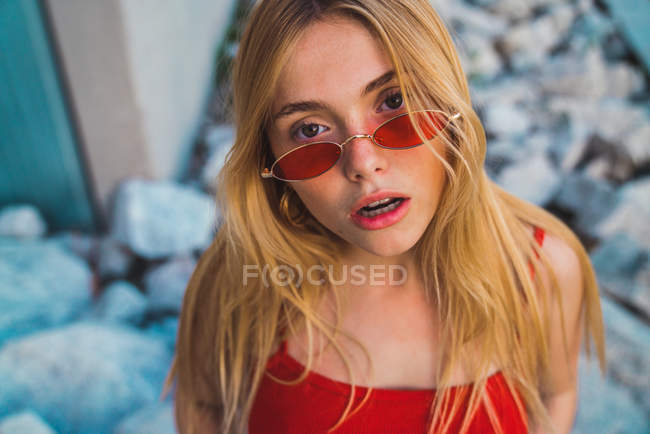 Blonde young female in red sunglasses looking at camera outdoors — Stock Photo